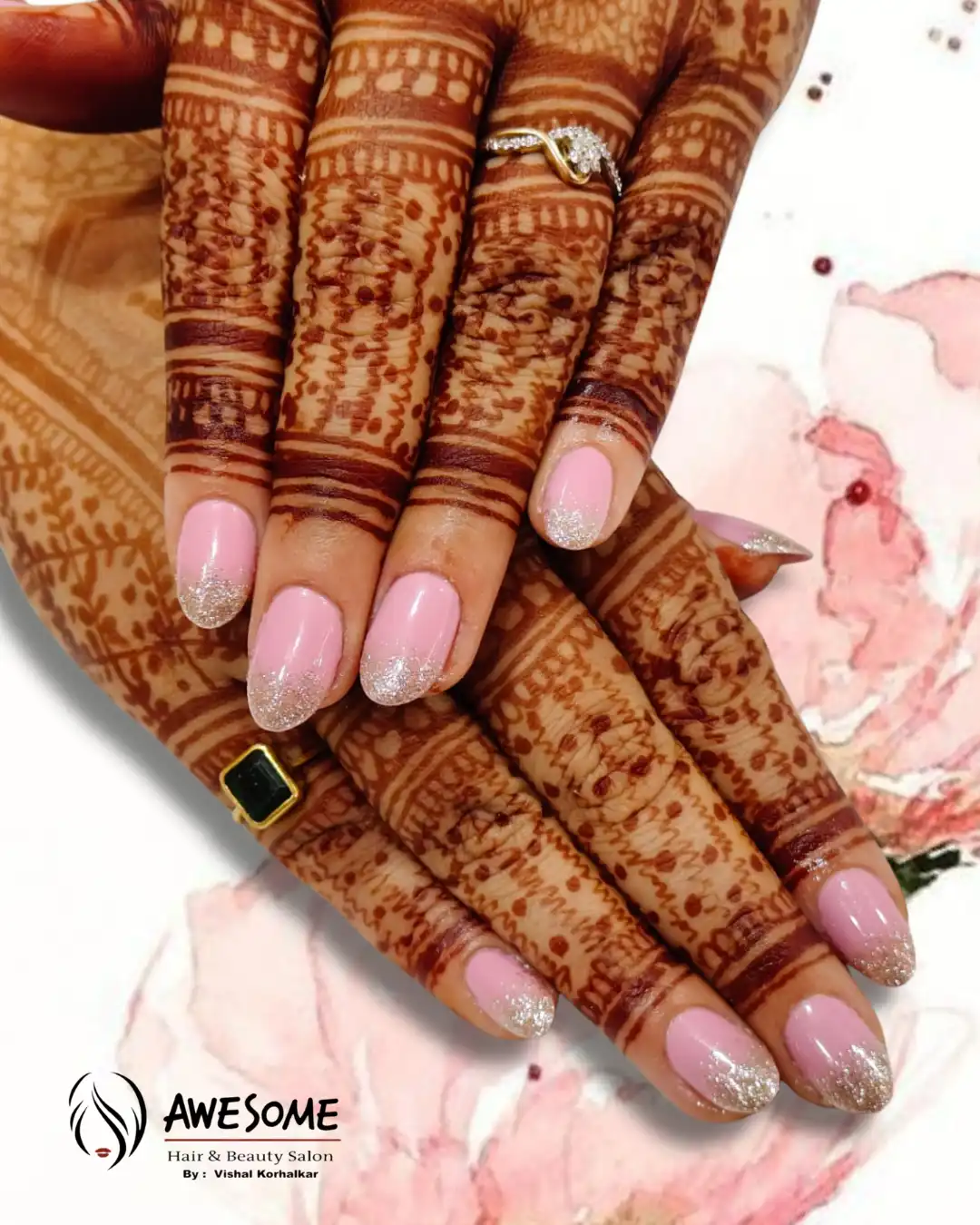 Close-up of bridal hands with intricate henna mehndi design and soft pink gel nails featuring glitter French tips.
