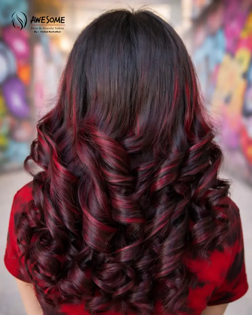 Voluminous curly hairstyle featuring dark brown hair with deep burgundy red highlights styled at Awesome Hair & Beauty Salon