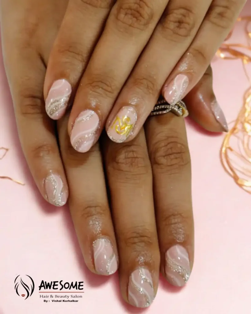 Close-up of hands showing elegant pink gel manicure with white and silver glitter swirl nail art design, featuring a soft glossy finish and decorative accent nail, done at a professional beauty salon.